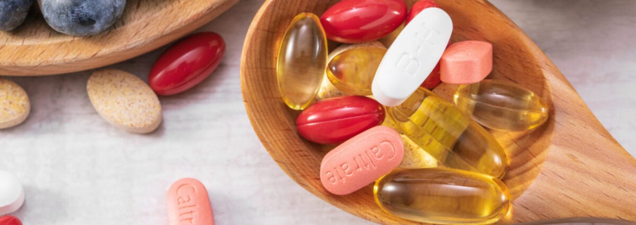 A closeup shot of fresh fruits with different medicine on a wooden spoon